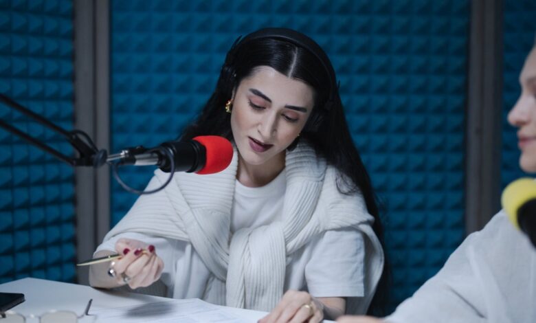 Dos mujeres conducen un programa de radio frente a micrófonos profesionales en un estudio