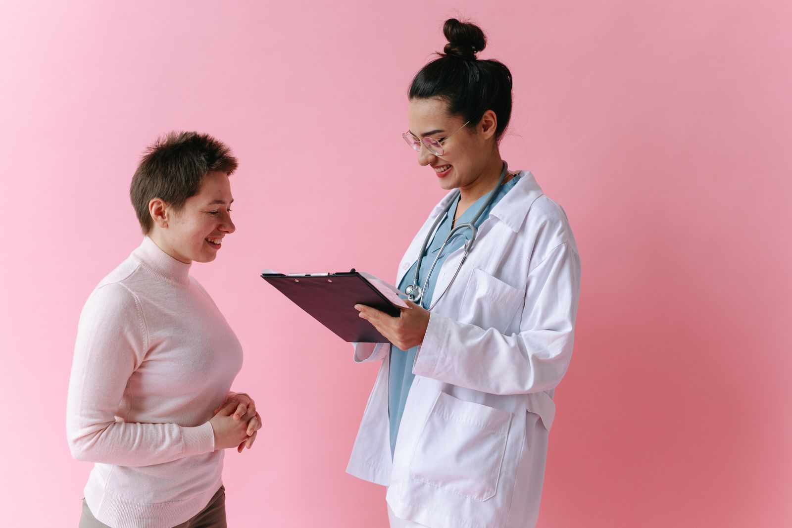 Médica con bata blanca conversa con una paciente durante una consulta