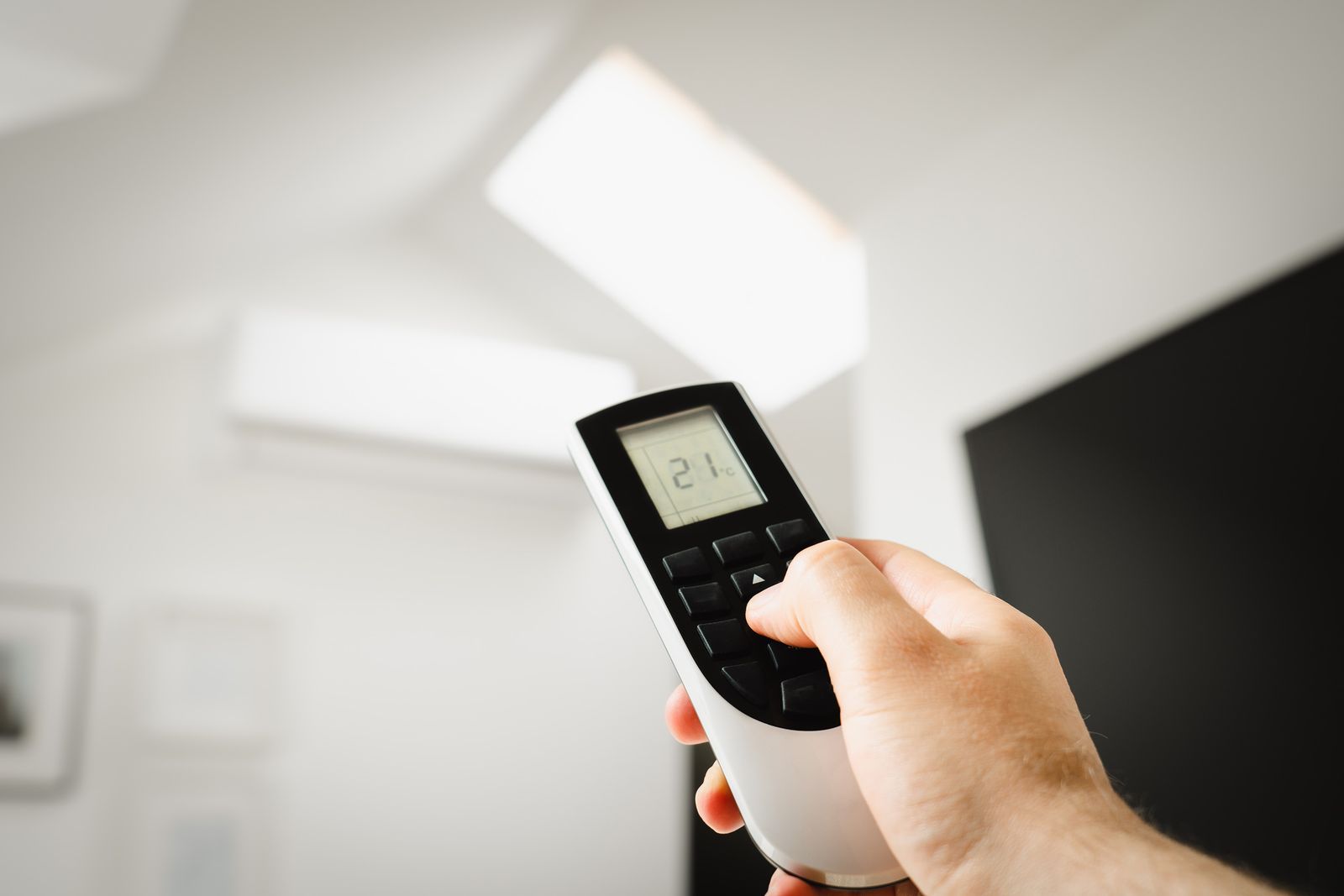 Mano usando el control remoto de un aire acondicionado