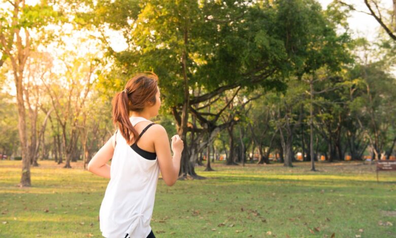 Mujer trotando por un parque arbolado temprano por la mañana