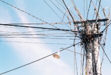 Poste de luz con cables de tendido eléctrico contra el cielo