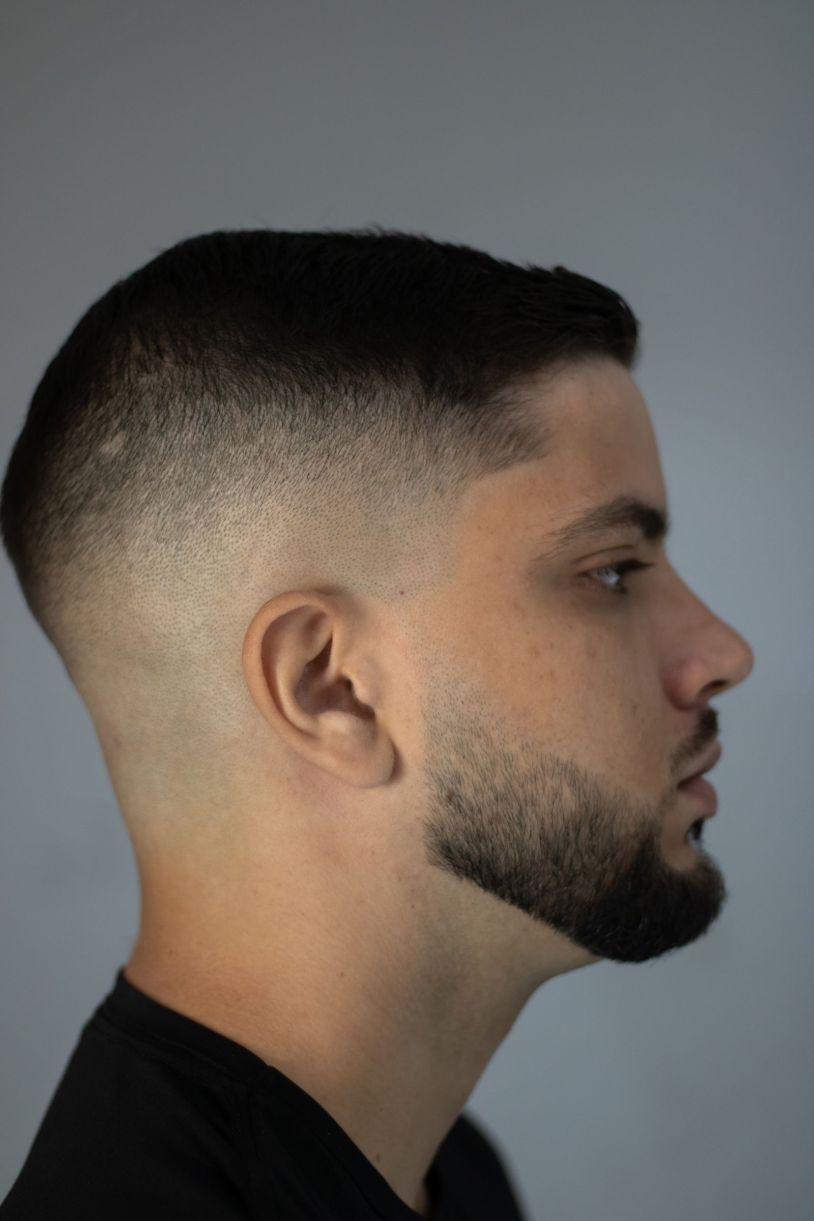 Perfil de un hombre con corte degradado bajo en los costados y barba prolija