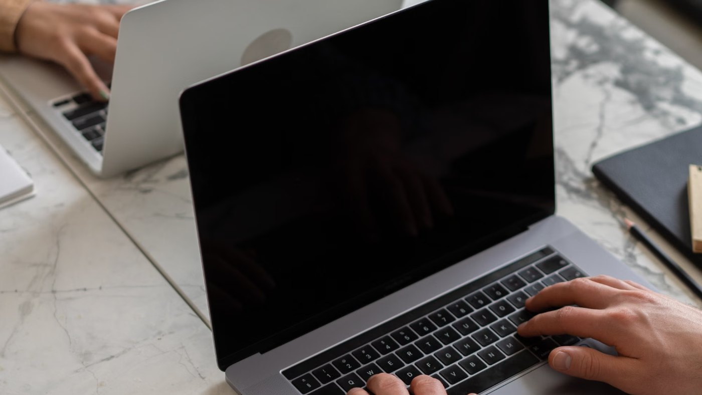 Manos escribiendo en una notebook sobre una mesa de trabajo