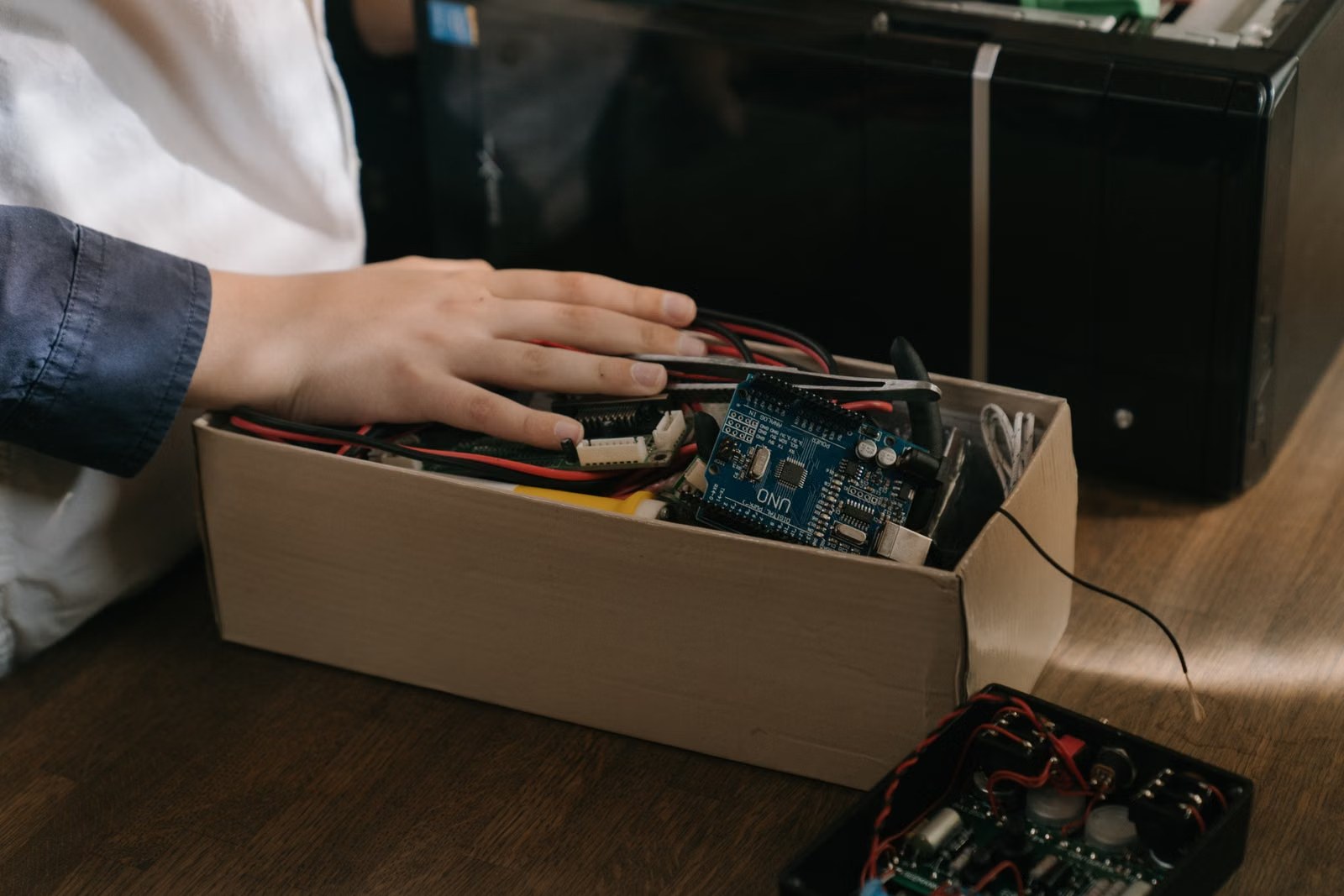 Manos trabajando con una placa de microcontrolador y cables, como en el curso de sistemas inteligentes