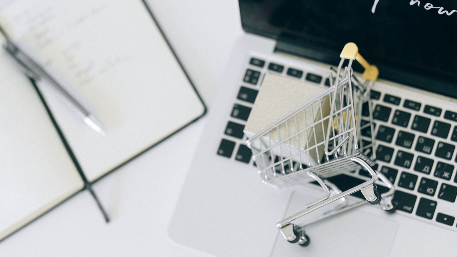 Carrito de compras en miniatura sobre una notebook