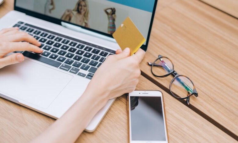Persona con una tarjeta en la mano mientras compra en una notebook