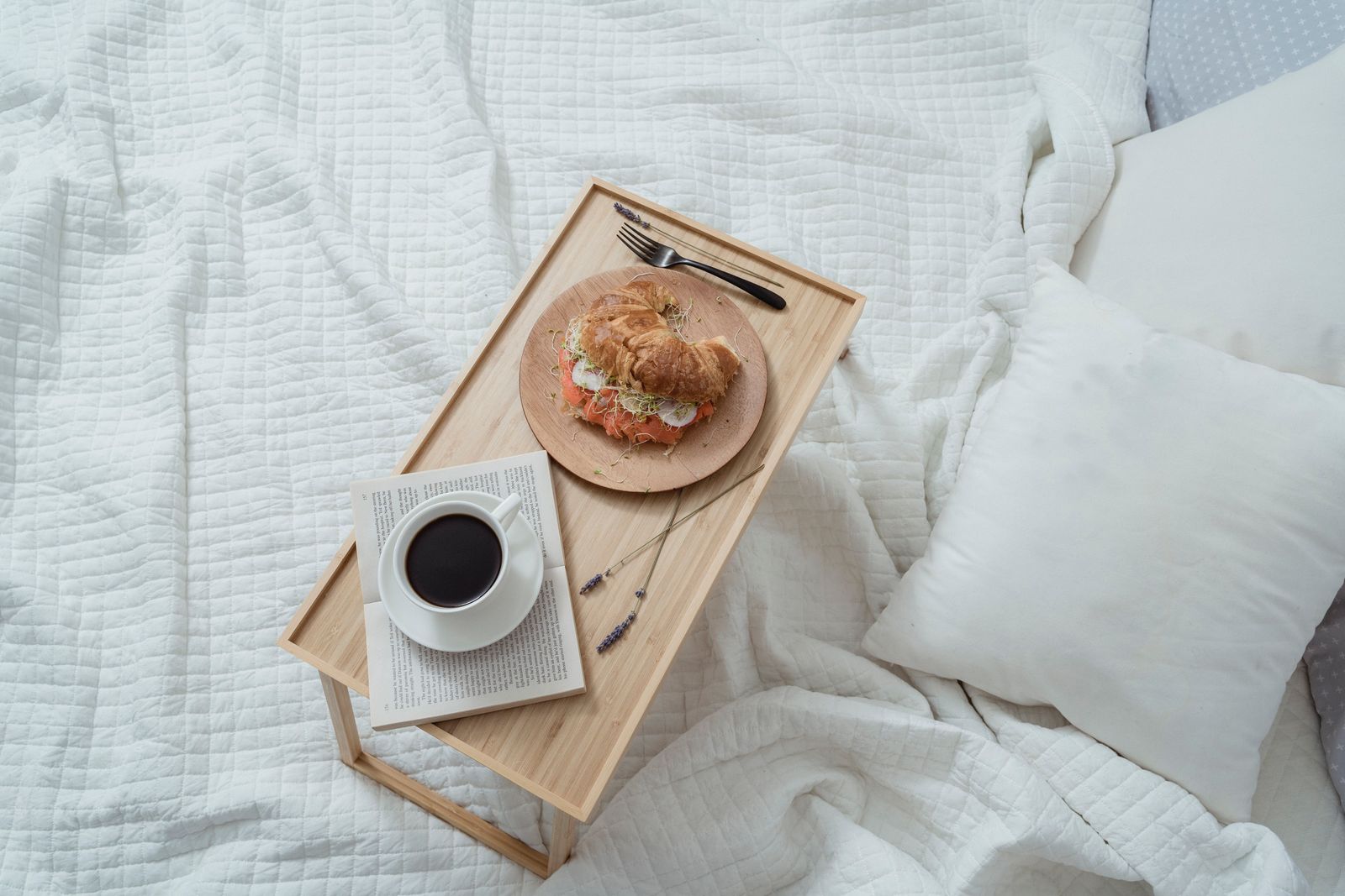 Bandeja de desayuno en la cama con café y croissant