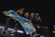 Hinchas argentinos con una bandera celeste y blanca de noche, celebrando un partido de la Selección