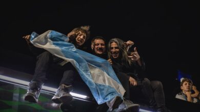 Hinchas argentinos con una bandera celeste y blanca de noche, celebrando un partido de la Selección