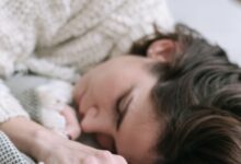 Mujer durmiendo de costado sobre la cama con sábanas blancas