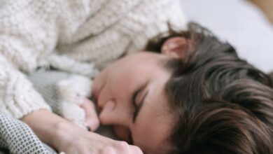 Mujer durmiendo de costado sobre la cama con sábanas blancas