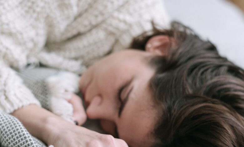 Mujer durmiendo de costado sobre la cama con sábanas blancas
