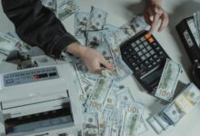Manos con calculadora, billetes y notebook sobre una mesa de madera