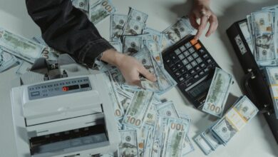 Manos con calculadora, billetes y notebook sobre una mesa de madera