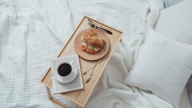 Bandeja de desayuno con café y medialuna sobre una cama