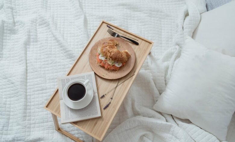 Bandeja de desayuno con café y medialuna sobre una cama