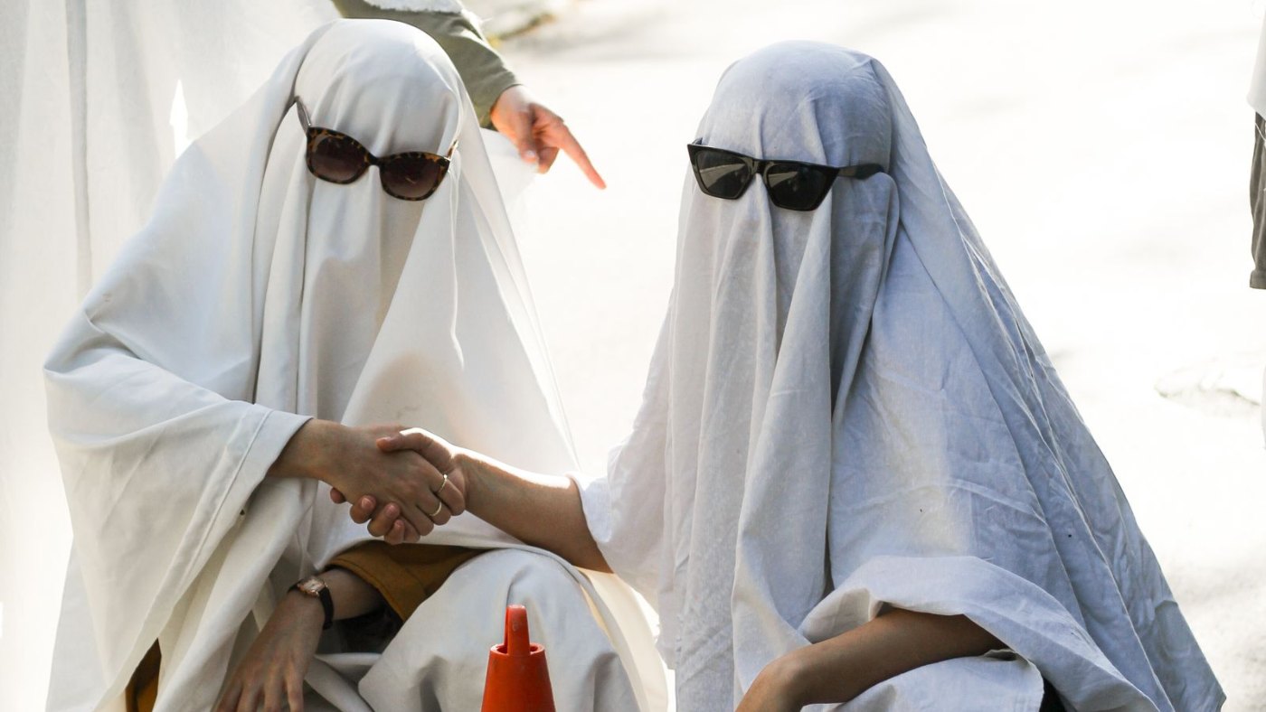 Dos personas disfrazadas de fantasma con sábanas blancas y anteojos de sol