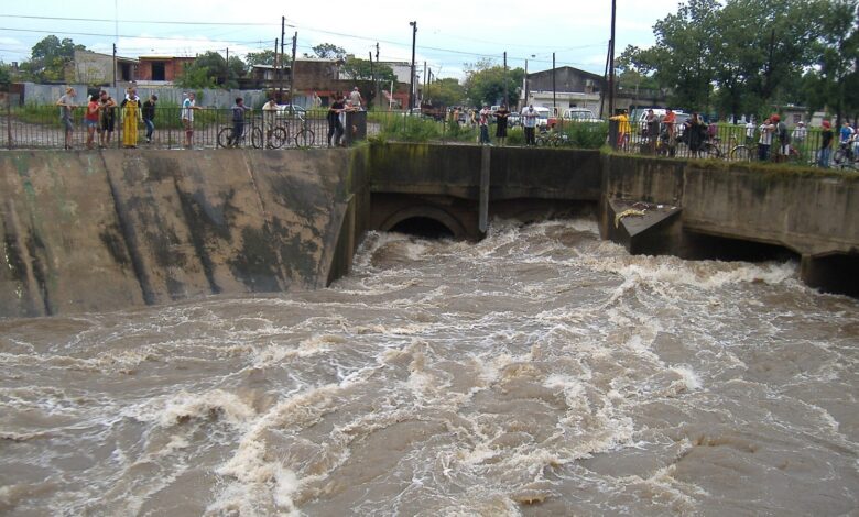 Arroyo Ludueña crecido en Rosario, con vecinos mirando el agua desde la baranda