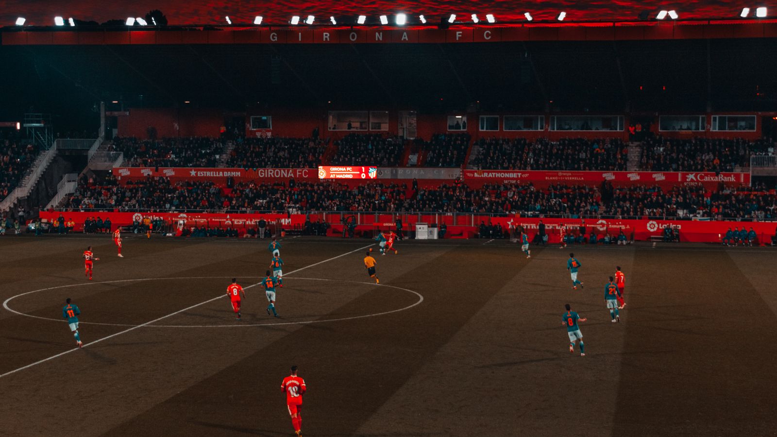 Partido de fútbol en un estadio al atardecer