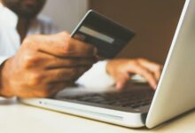 Persona usando una laptop con una tarjeta de crédito en la mano para comprar por internet