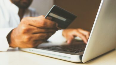 Persona usando una laptop con una tarjeta de crédito en la mano para comprar por internet