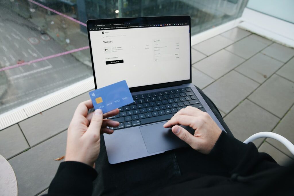 Persona comprando online con una notebook y una tarjeta en la mano