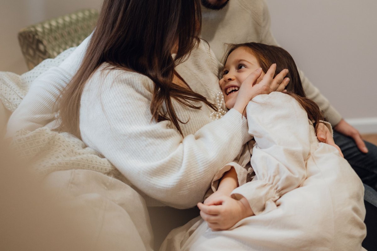 Padre abrazando a sus hijas en un sillón