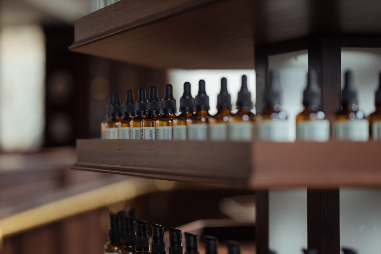 Frascos goteros de vidrio ámbar alineados en un estante de madera de una farmacia