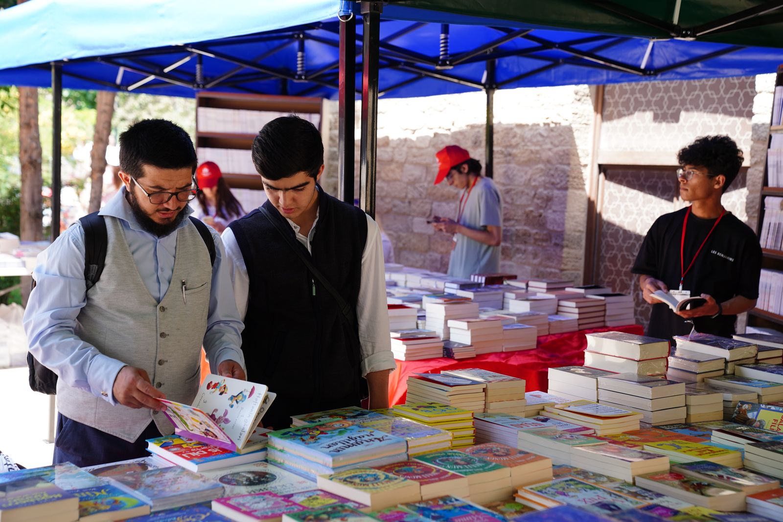 Personas hojeando libros en los puestos de una feria