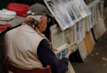 Hombre mayor leyendo historietas en un puesto de libros al aire libre