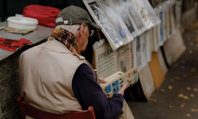 Hombre mayor leyendo historietas en un puesto de libros al aire libre