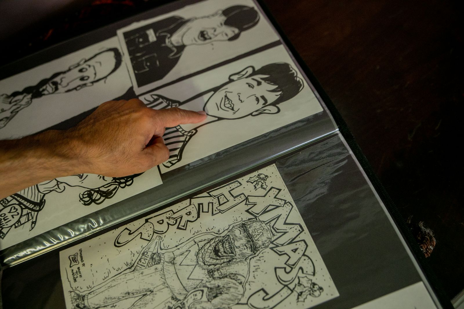 Mano señalando bocetos de caricaturas en una carpeta de dibujos