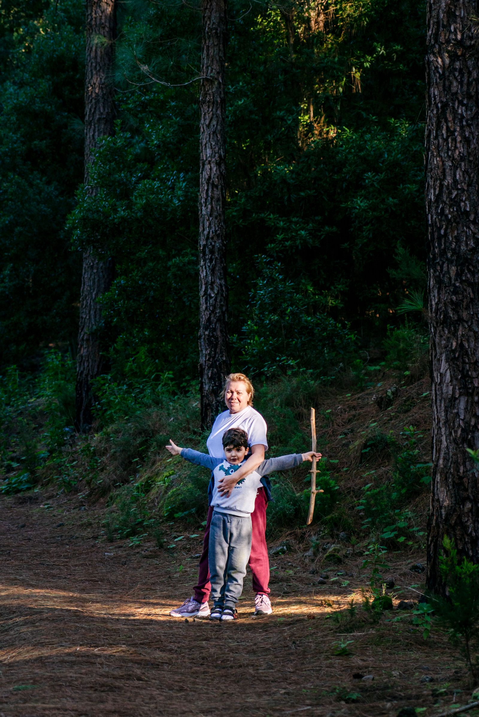 Dos chicos juegan en un bosque con los brazos abiertos, un plan al aire libre para el fin de semana largo