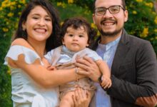 Familia con un bebé posa en un parque con flores durante un paseo de fin de semana