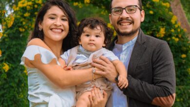 Familia con un bebé posa en un parque con flores durante un paseo de fin de semana