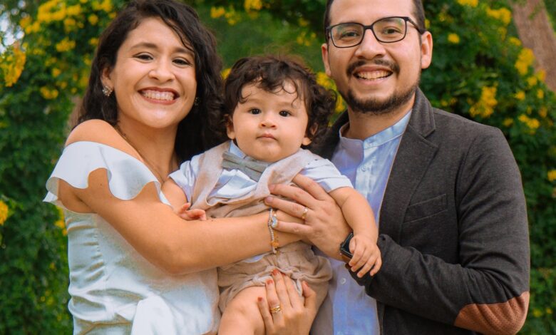 Familia con un bebé posa en un parque con flores durante un paseo de fin de semana