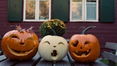 Tres calabazas talladas con caras sobre una mesa de madera