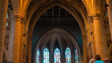 Interior de una iglesia con vitrales y fieles sentados en los bancos