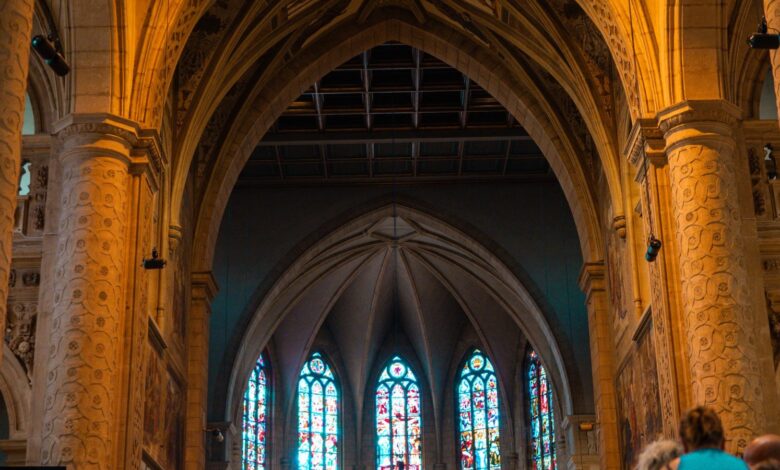 Interior de una iglesia con vitrales y fieles sentados en los bancos