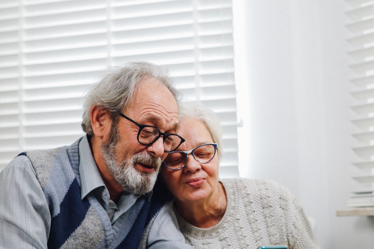 Pareja de adultos mayores sonriendo en su casa