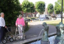 Pareja de adultos mayores caminando junto a una fuente en un parque