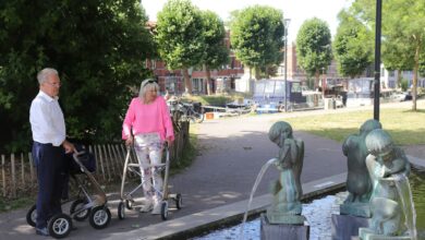 Pareja de adultos mayores caminando junto a una fuente en un parque
