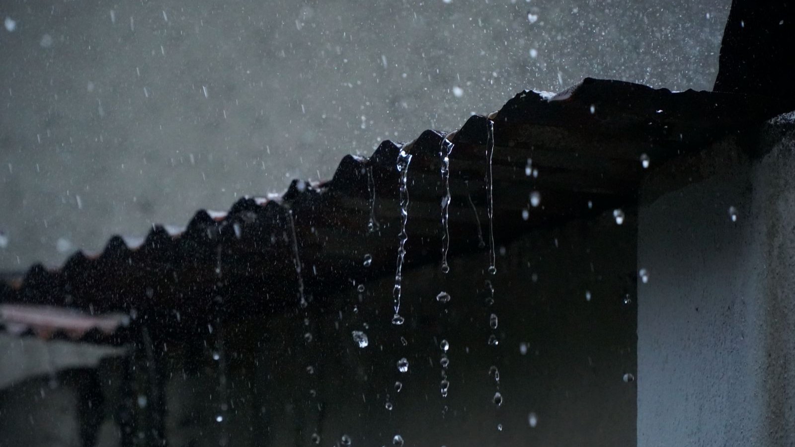 Agua de lluvia cayendo desde el borde de un techo