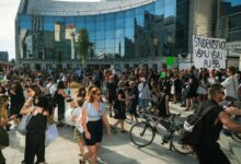 Estudiantes con carteles en una marcha frente a un edificio