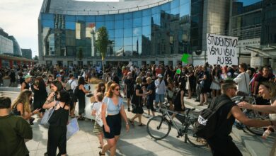 Estudiantes con carteles en una marcha frente a un edificio