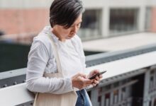 Mujer mirando su celular con gesto atento en una calle