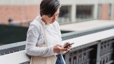 Mujer mirando su celular con gesto atento en una calle