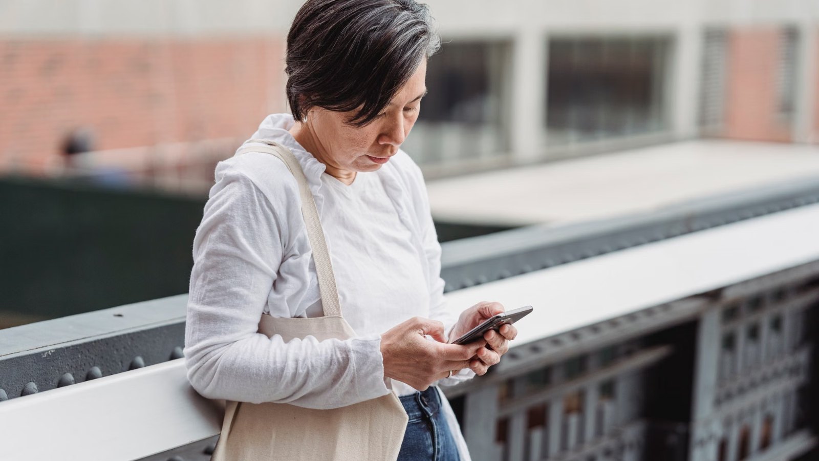 Mujer mirando su celular con gesto atento en una calle