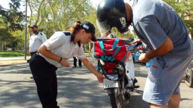 Agente municipal revisa la chapa patente de una moto durante un control en una calle arbolada de Rosario