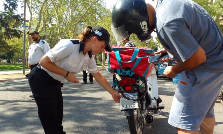 Agente municipal revisa la chapa patente de una moto durante un control en una calle arbolada de Rosario